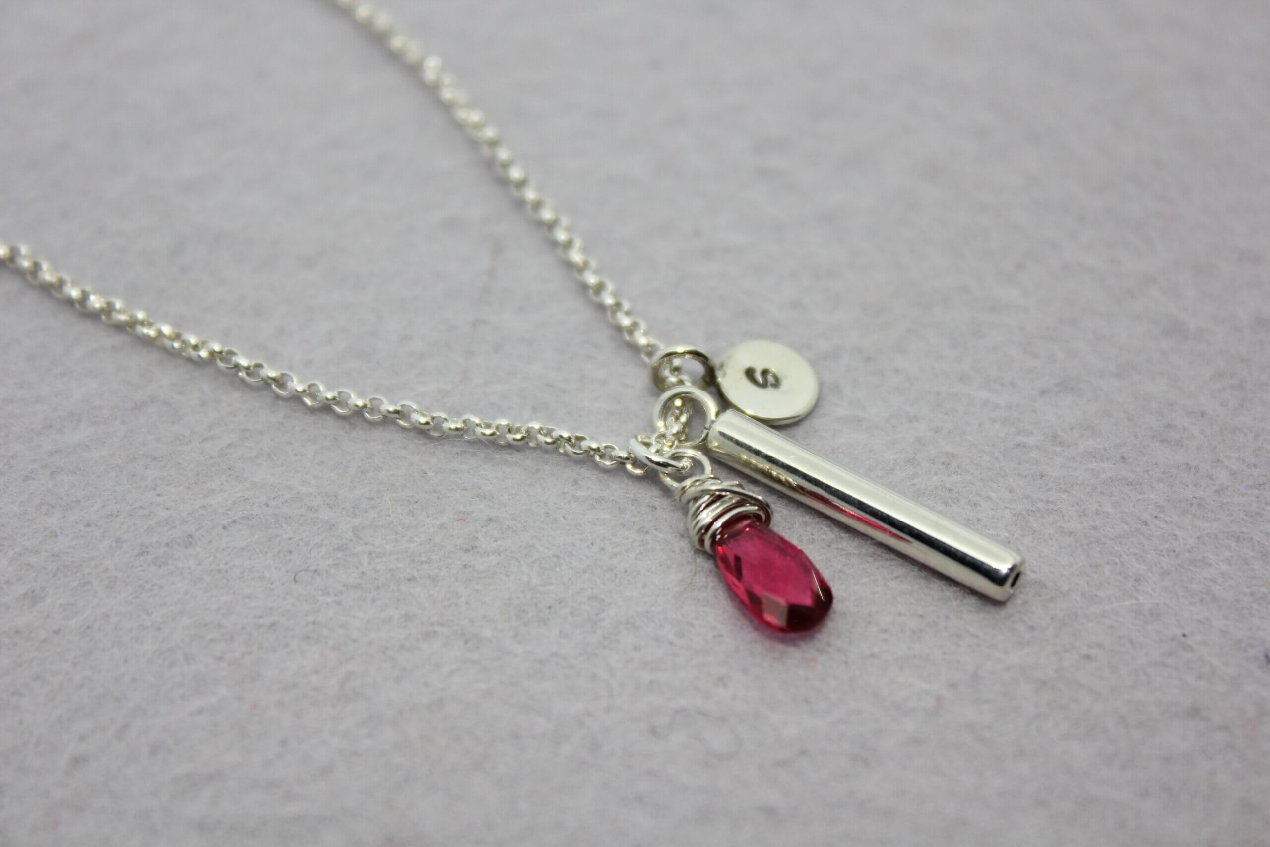 As sieraad van witgoud met edelsteen en letter, collier met vulbaar buisje